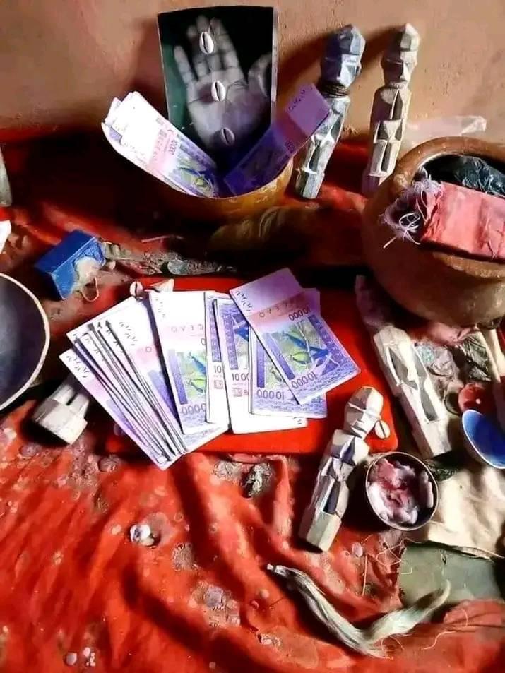 Espace de travail de Maître Cherif avec outils rituels : cauris, statuettes ancestrales, billets symboliques pour rituels de prospérité